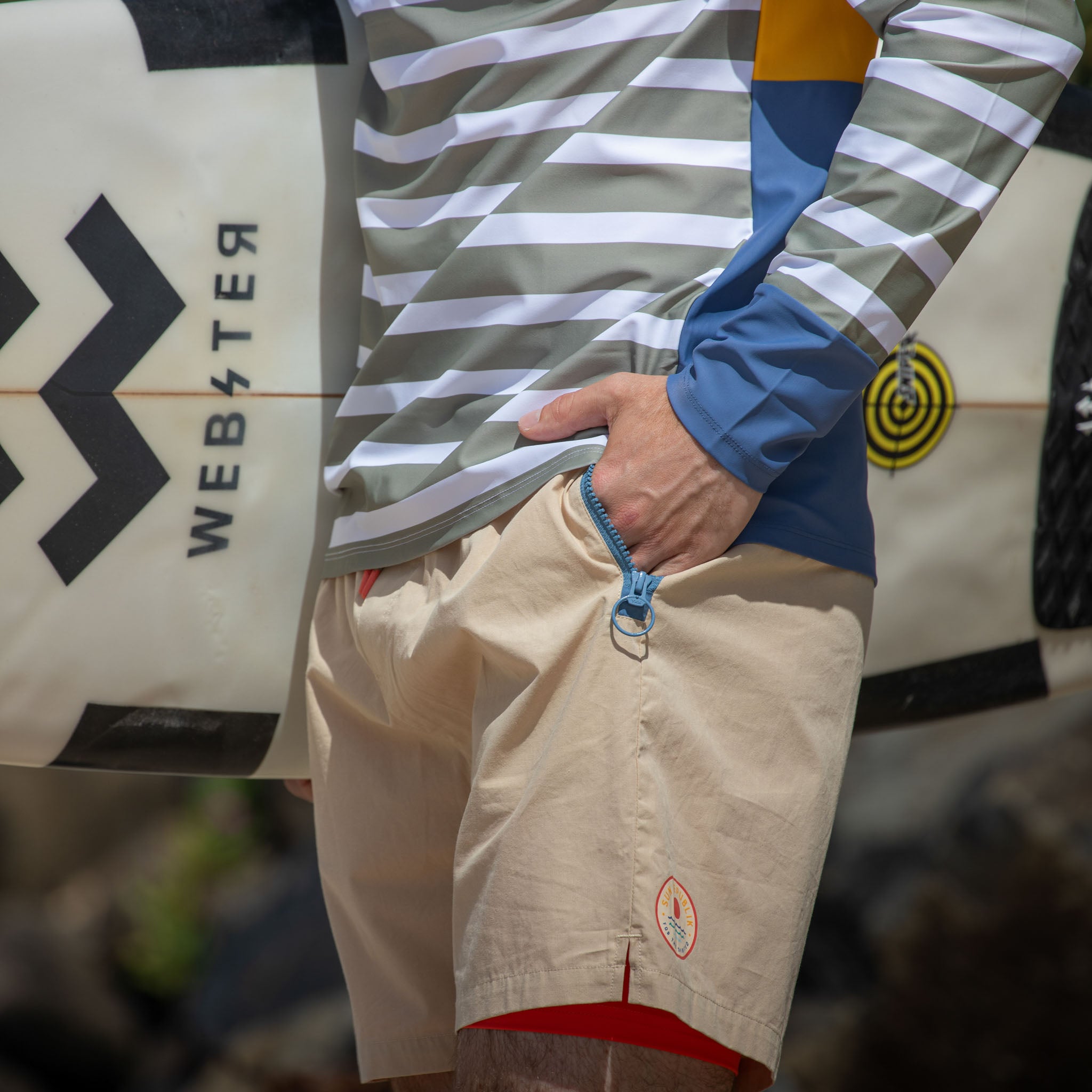 Man holding surfboard wearing mens beach wear with inner liner and zip pocket.