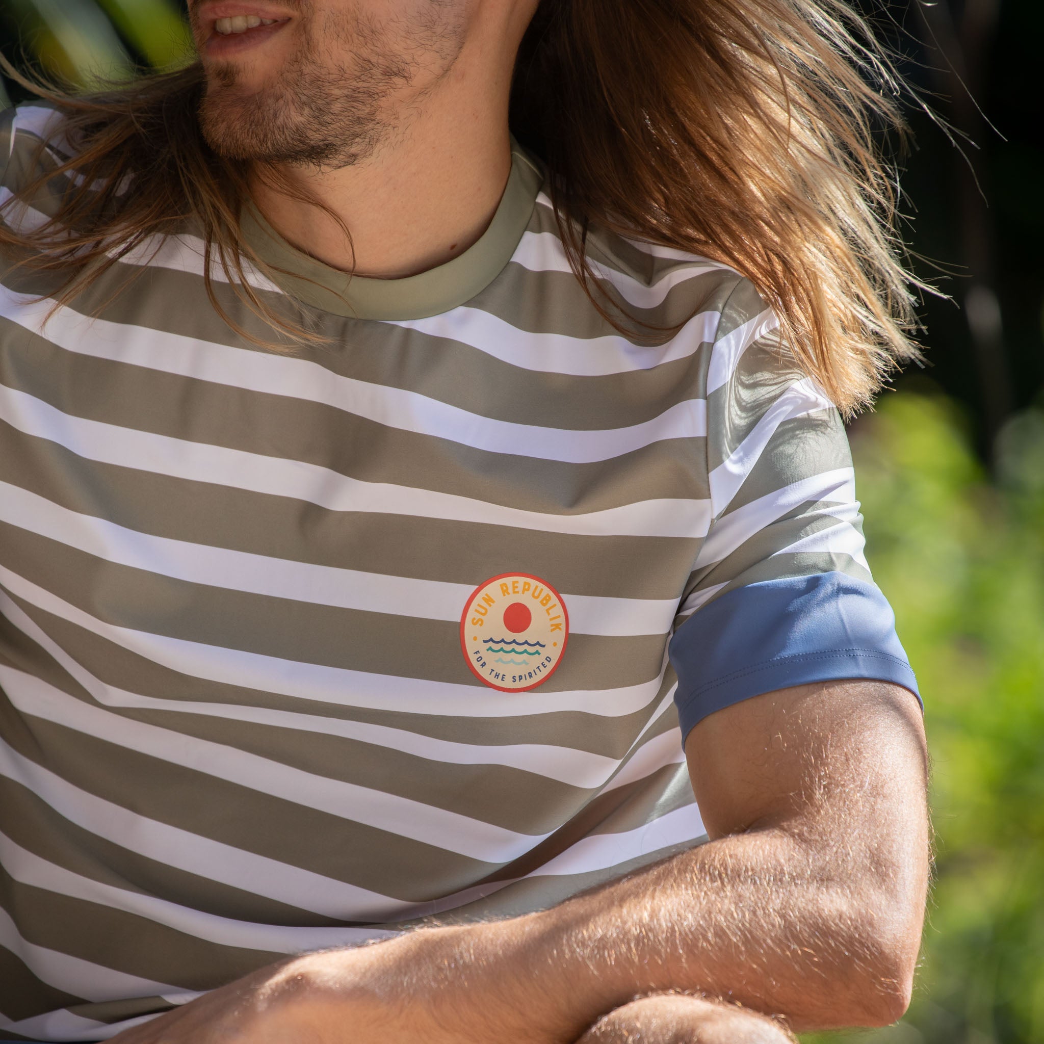 Close cropped view of mens beach wear swim shirt with cuff detail and logo.
