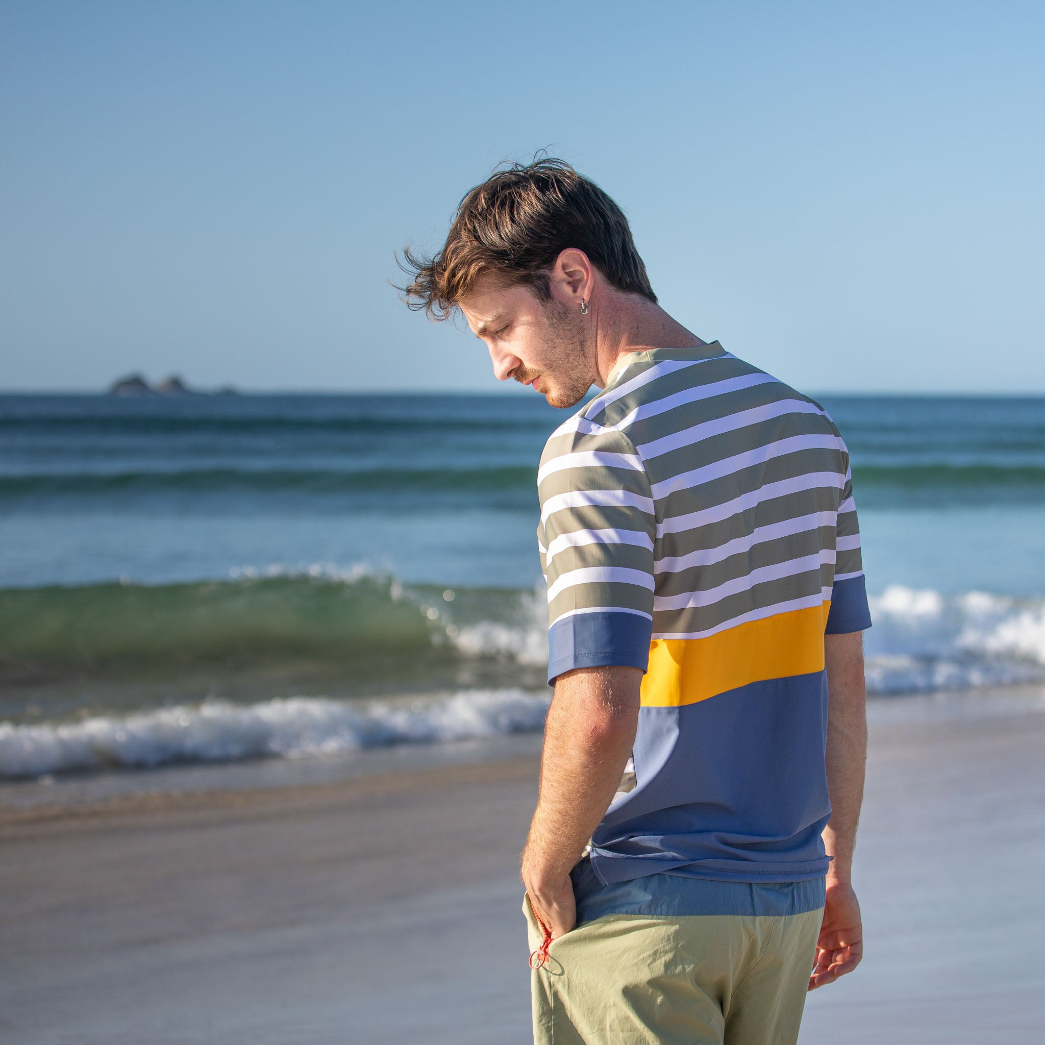 Men standing by sea wearing mens beach wear swim top, short sleeve.
