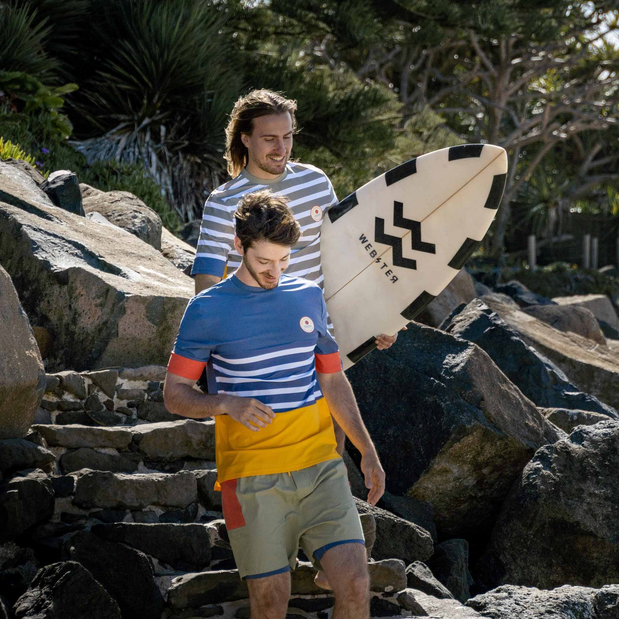 Men wearing beach wear swim top and shorts walking down stairs.