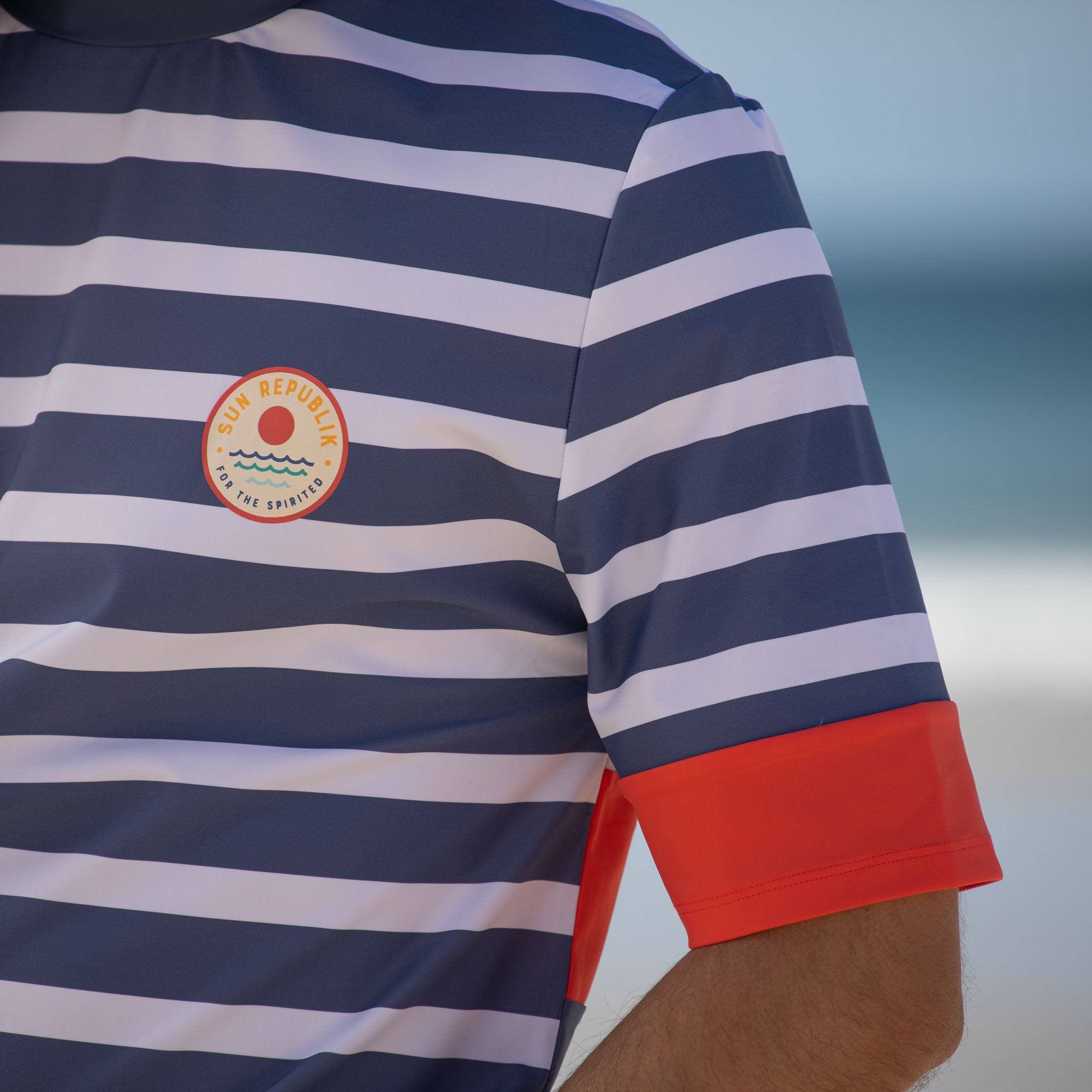Close cropped view of mens beach wear swim shirt with cuff detail and logo.