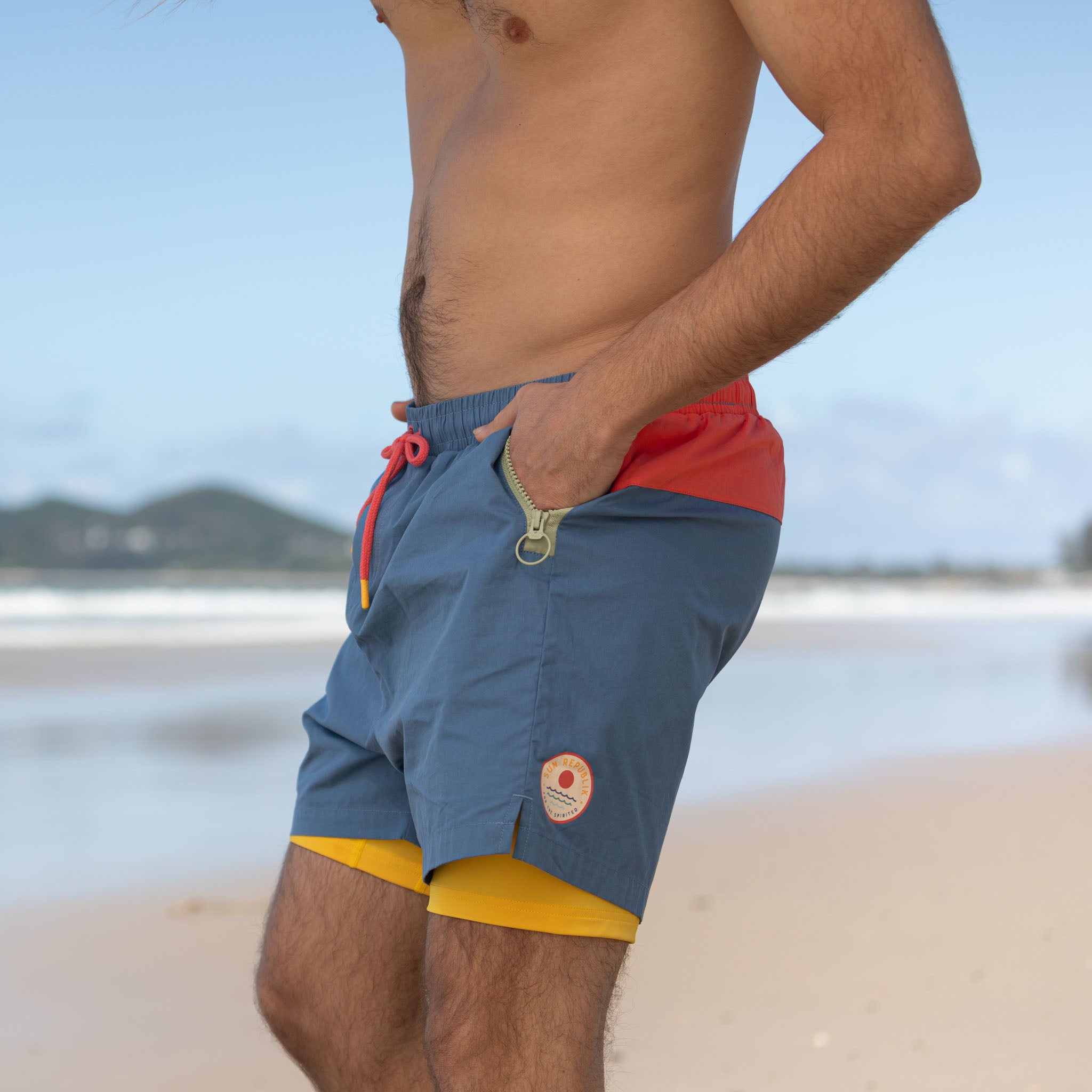 Man wearing mens beach wear with  yellow inner liner and zip pocket.