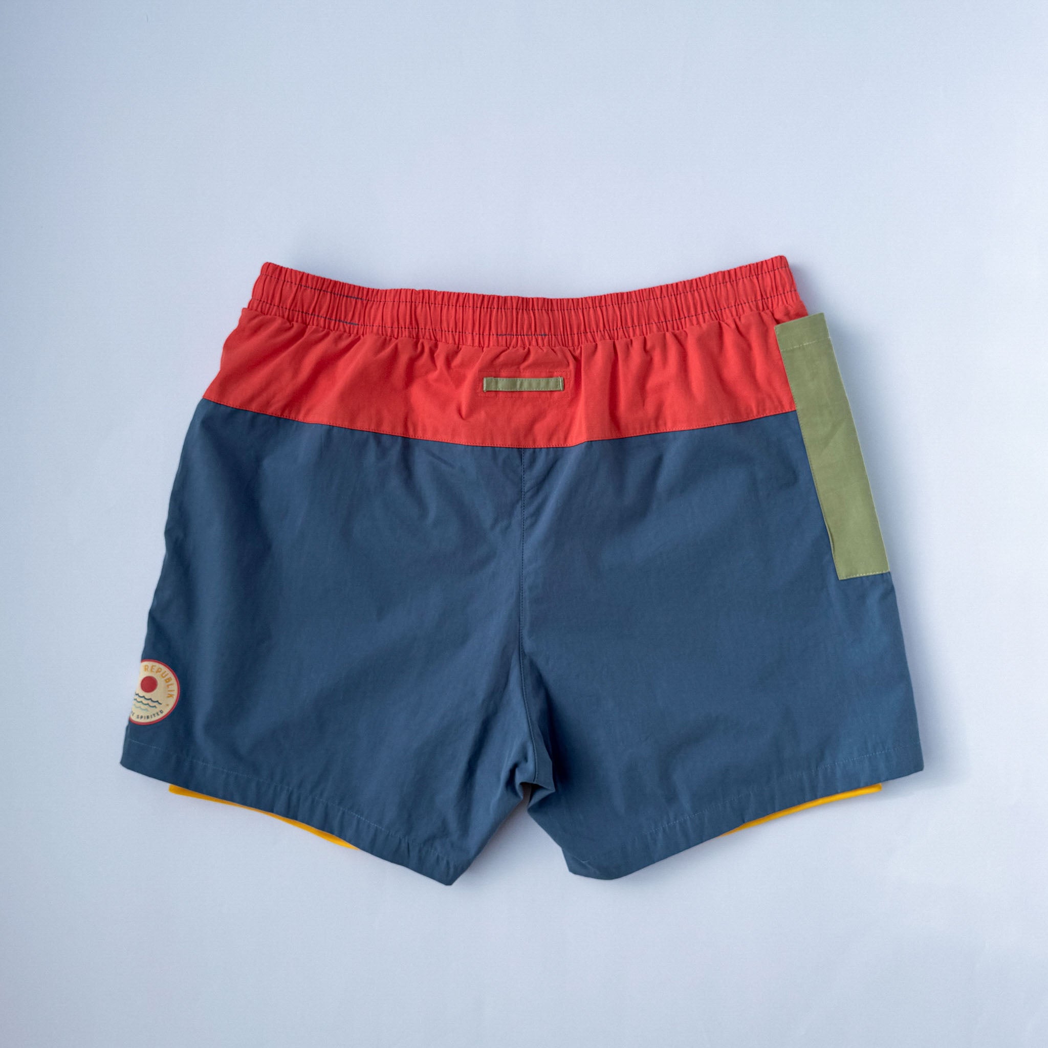 Back view of mens swimwear with inner liner and green phone pocket. On white background.