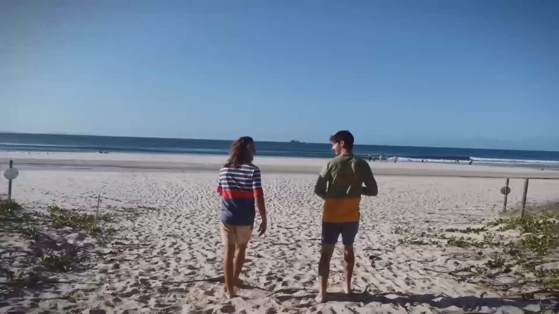 Men on beach in mens rashies, mens swim shirt and mens beach shorts