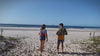 Men on beach in mens rashies, mens swim shirt and mens beach shorts